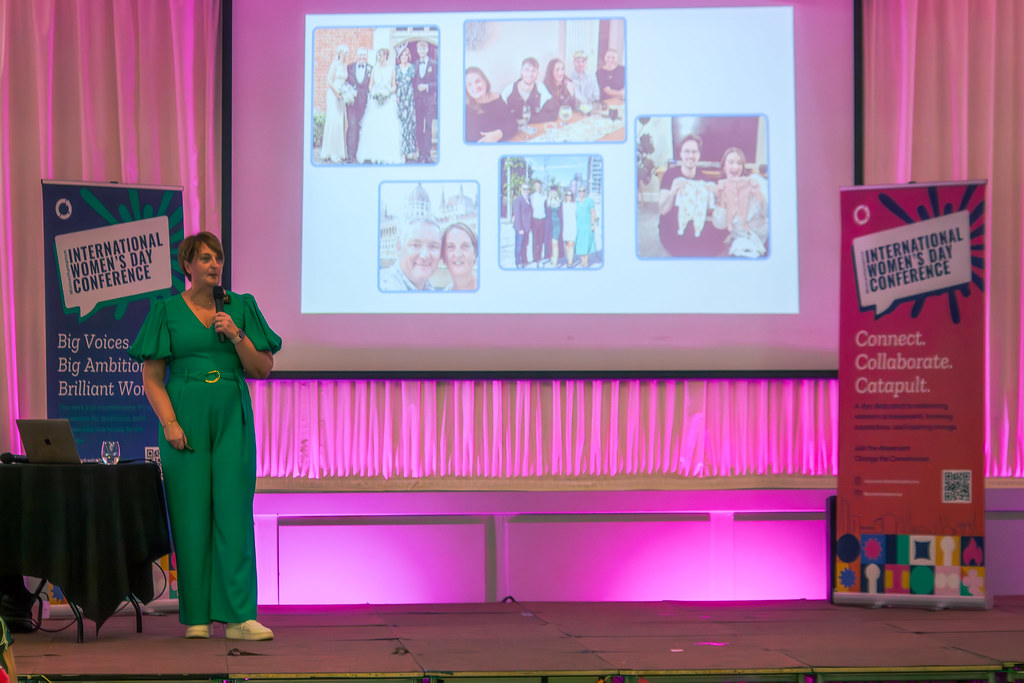 Emma-Thompson-Wolverhampton-International-Women's-Day-Conference-3- Credit-Anna-Mhairi-Kane Angle shot of Emma Thompson speaking on stage at Wolverhampton International Women's Day Conference. Emma is wearing a fabulous green jumpsuit and holding a microphone